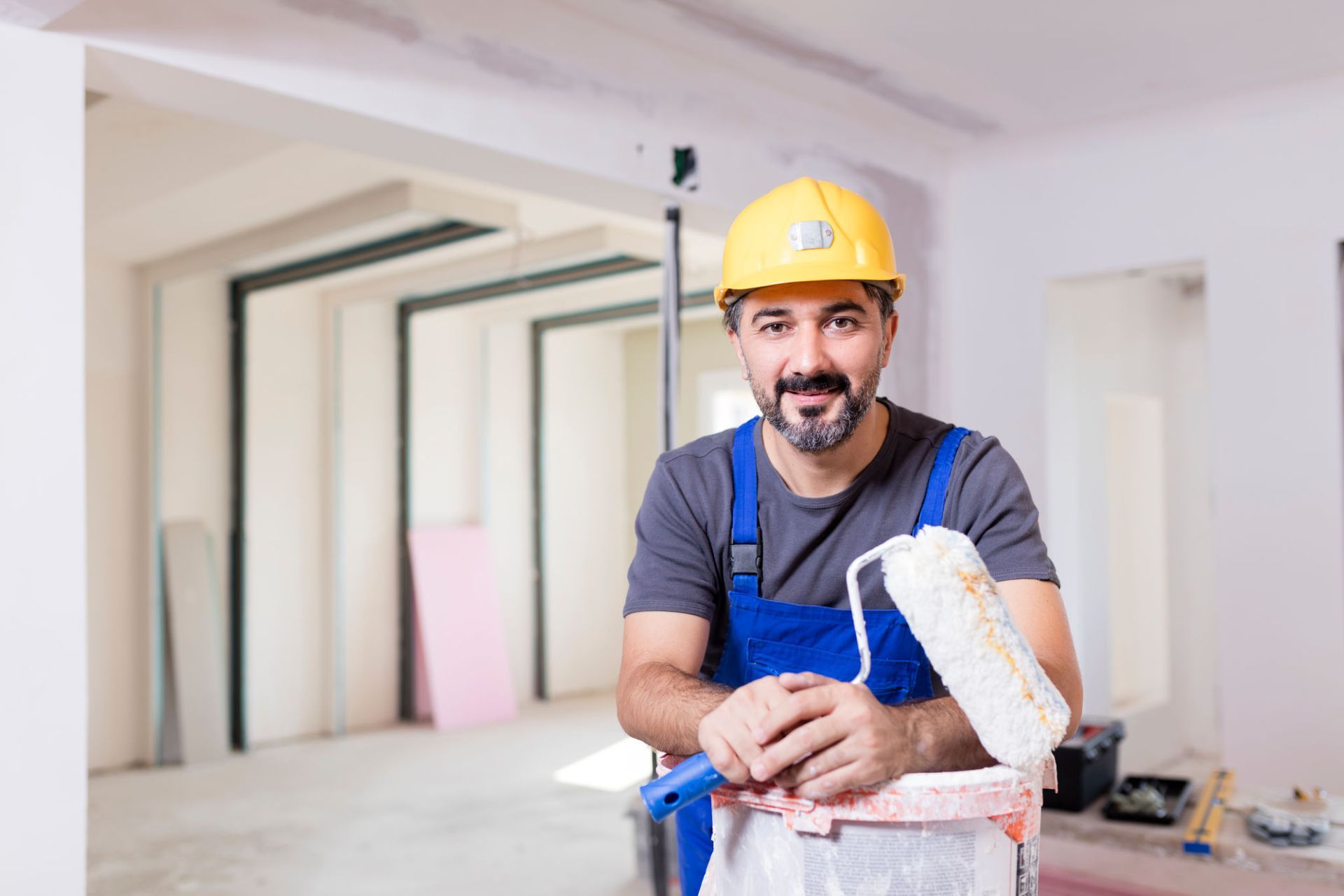 A man in a hard hat is holding a paint roller in a room — Overland Park, KS — Johnson County Solutions