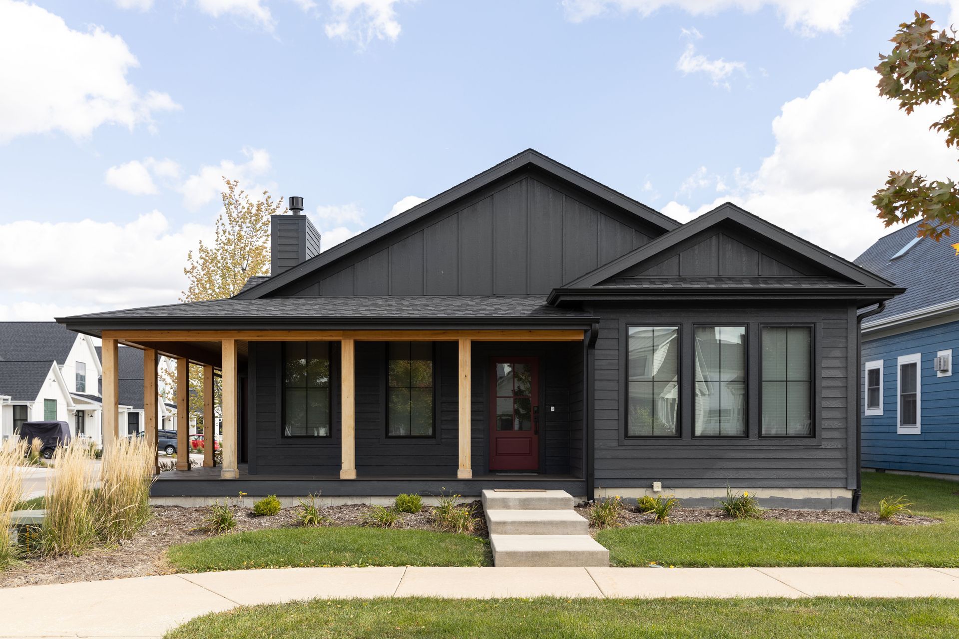 A black house with a porch and a blue house in the background — Overland Park, KS — Johnson County Solutions