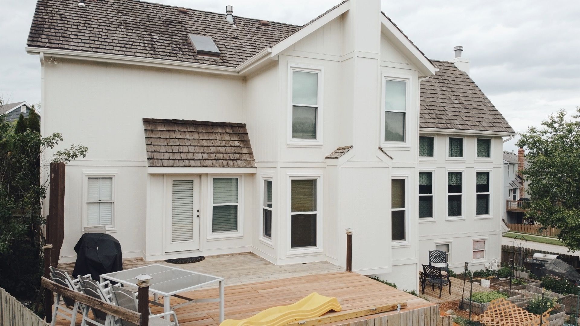 A large white house with a wooden roof and a patio in front of it — Overland Park, KS — Johnson County Solutions