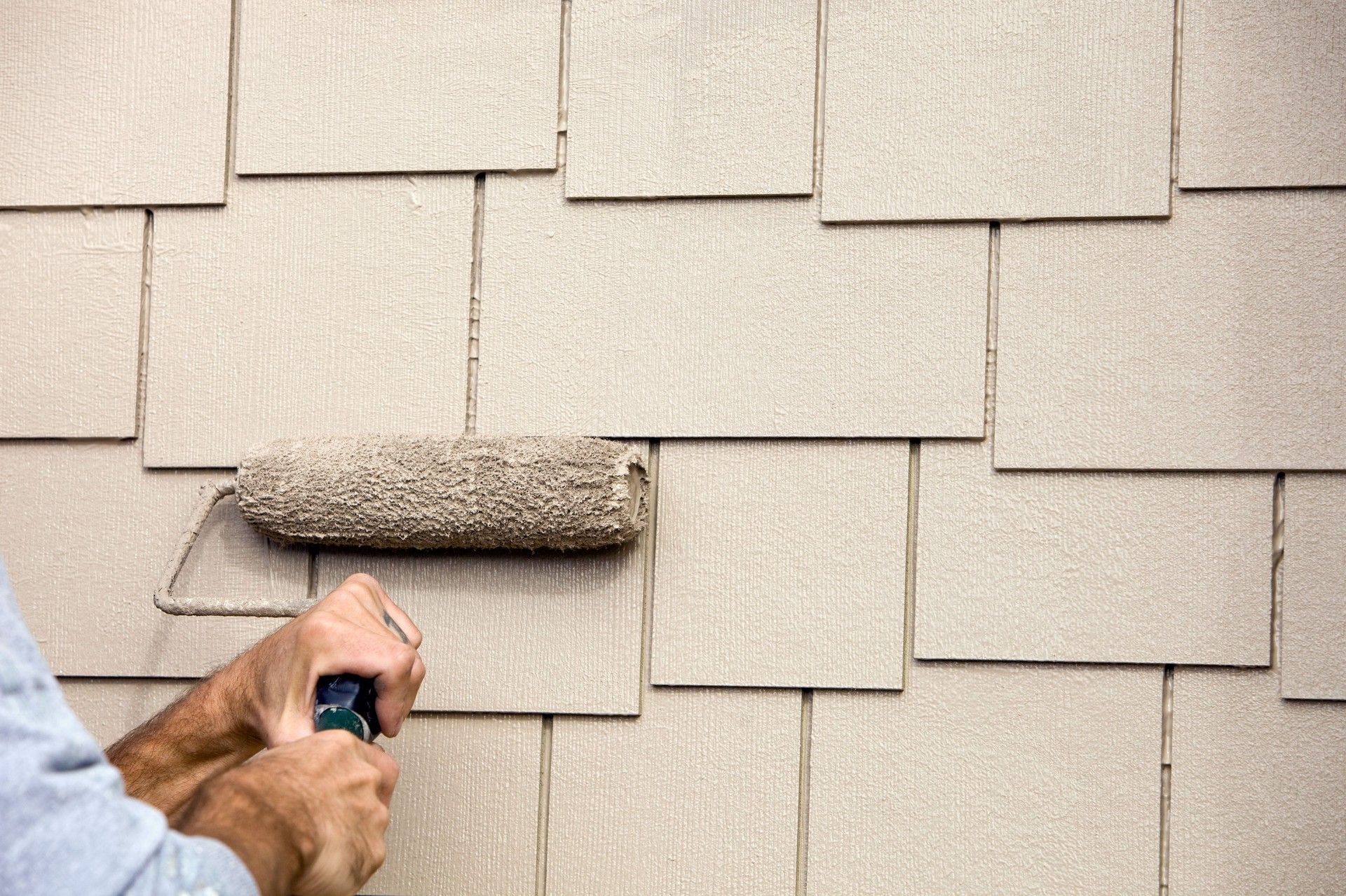 A man is painting a roof with a roller — Overland Park, KS — Johnson County Solutions