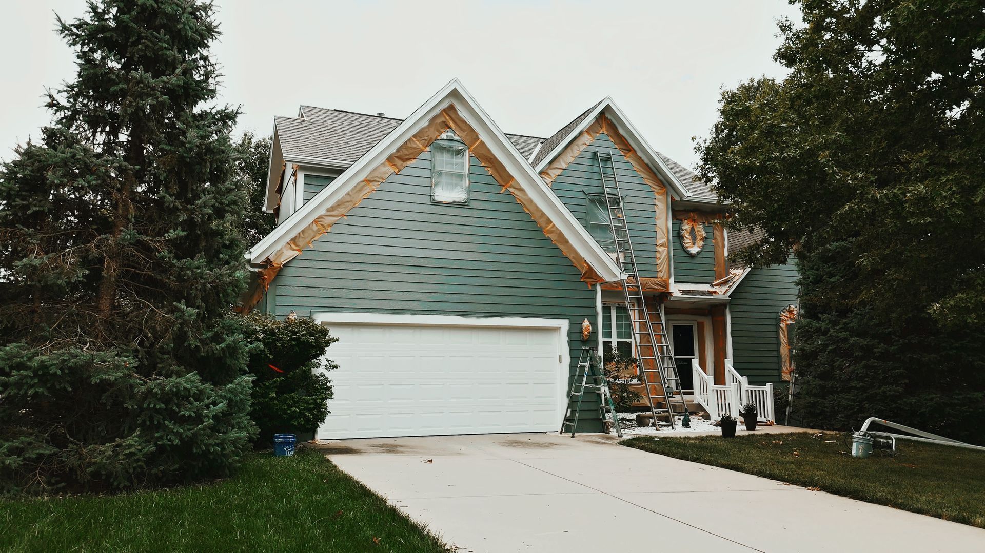 A large green house with a white garage door is surrounded by trees — Overland Park, KS — Johnson County Solutions