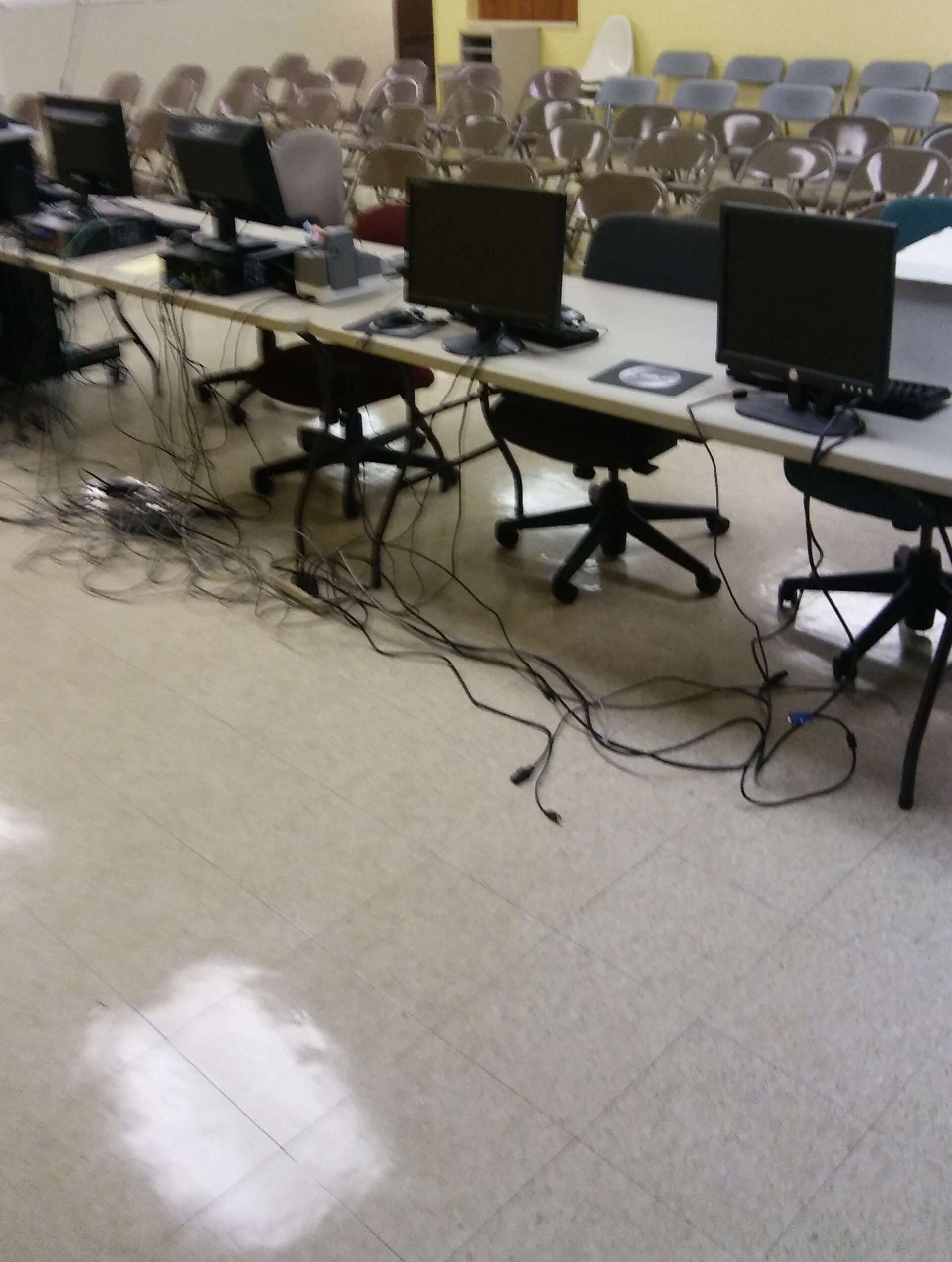 A row of computers are sitting on tables in a room
