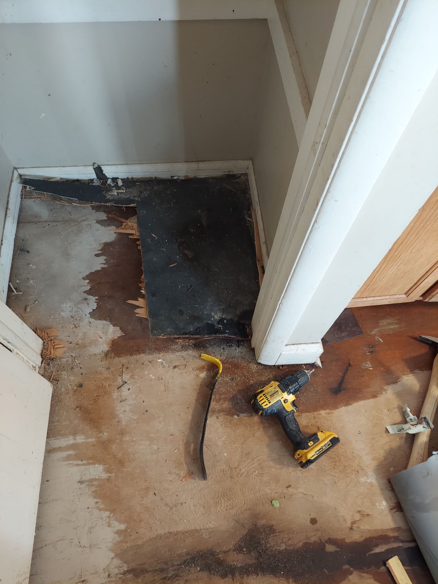 A drill is sitting on the floor of a room next to a door.