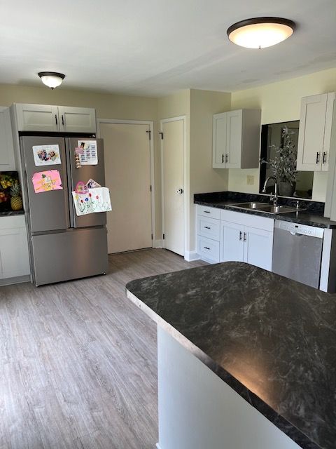 A kitchen with white cabinets and a stainless steel refrigerator