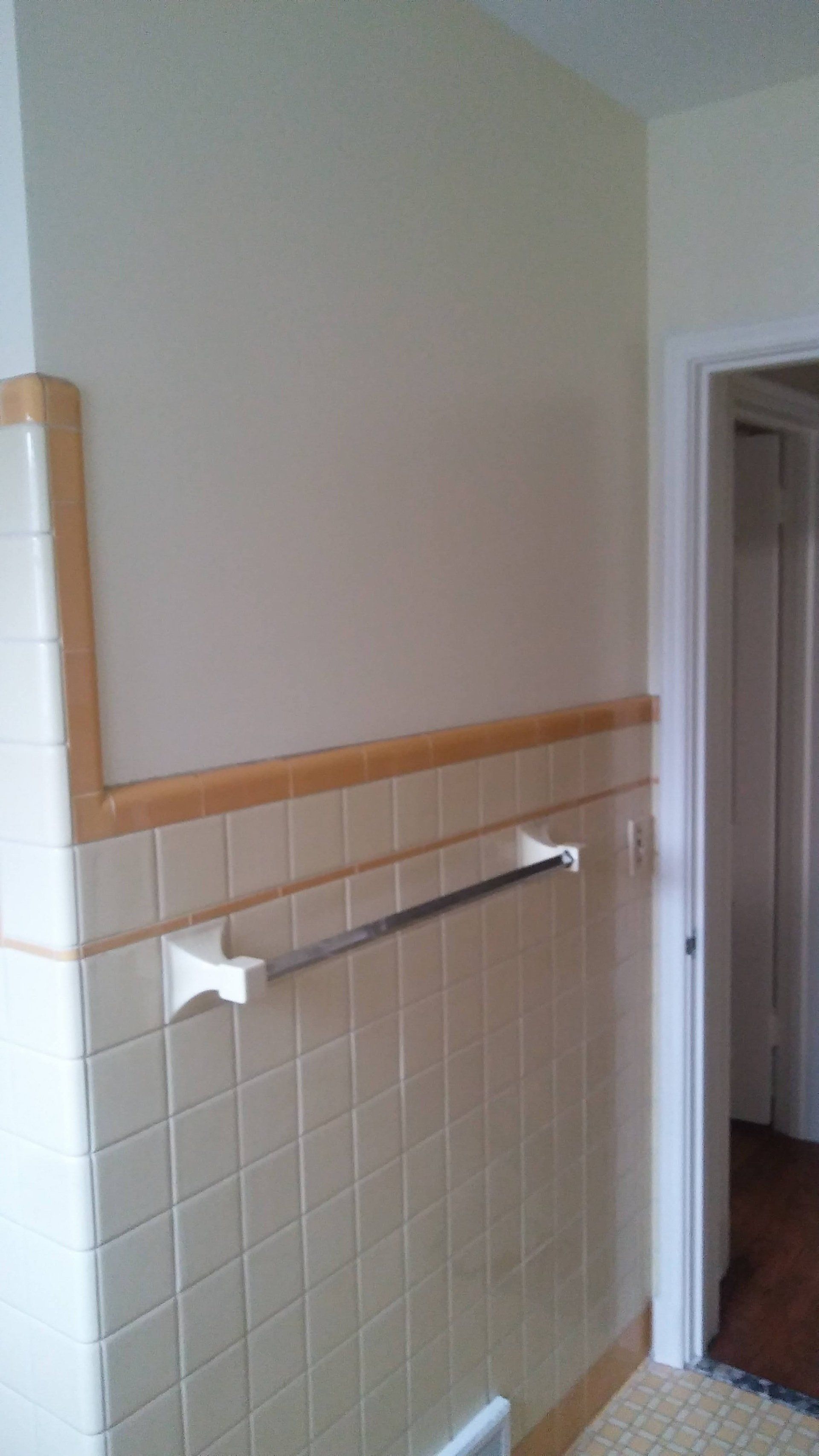 A bathroom with white tiles and a towel rack on the wall.