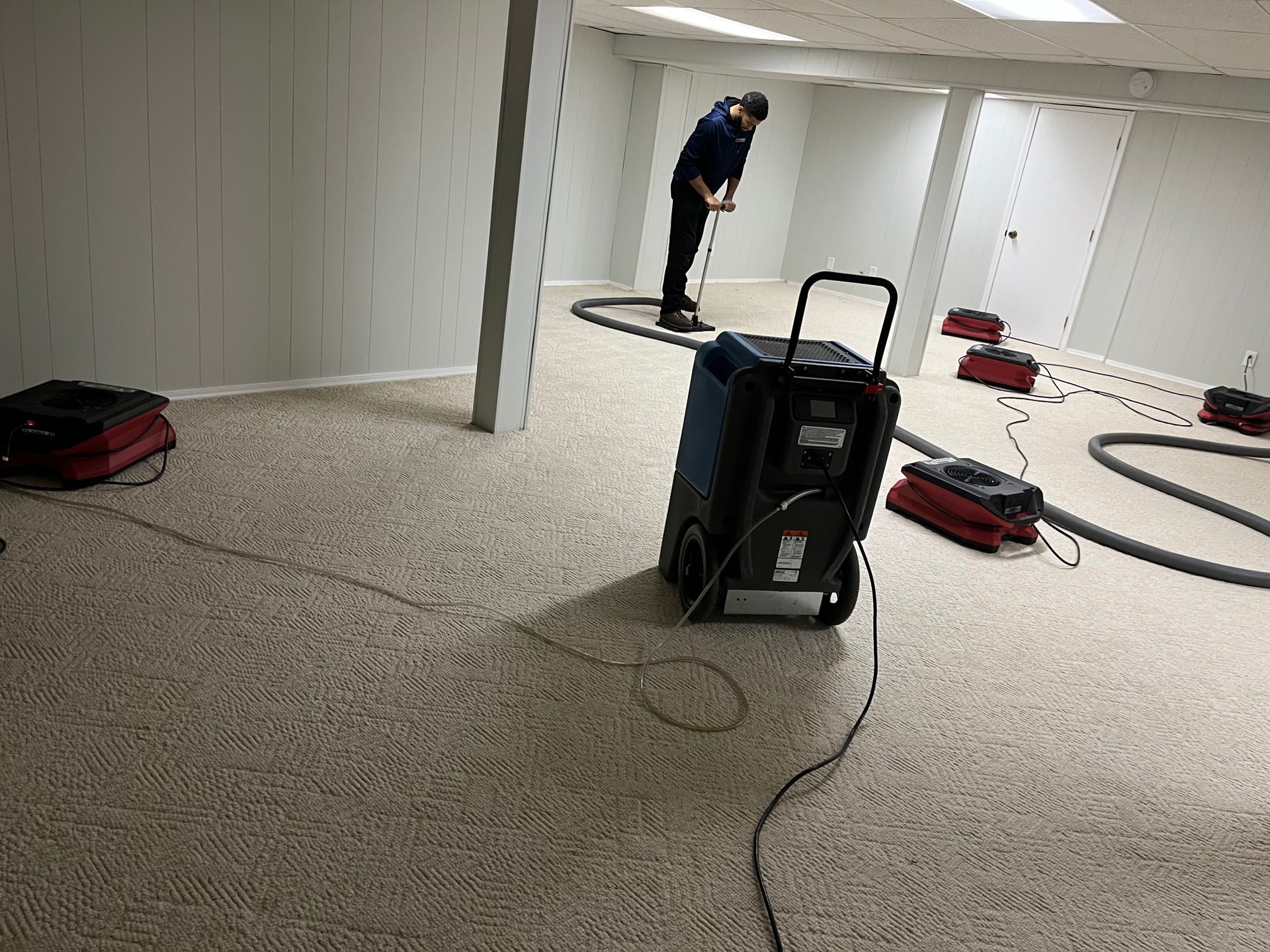 A man is cleaning a basement with a vacuum cleaner.