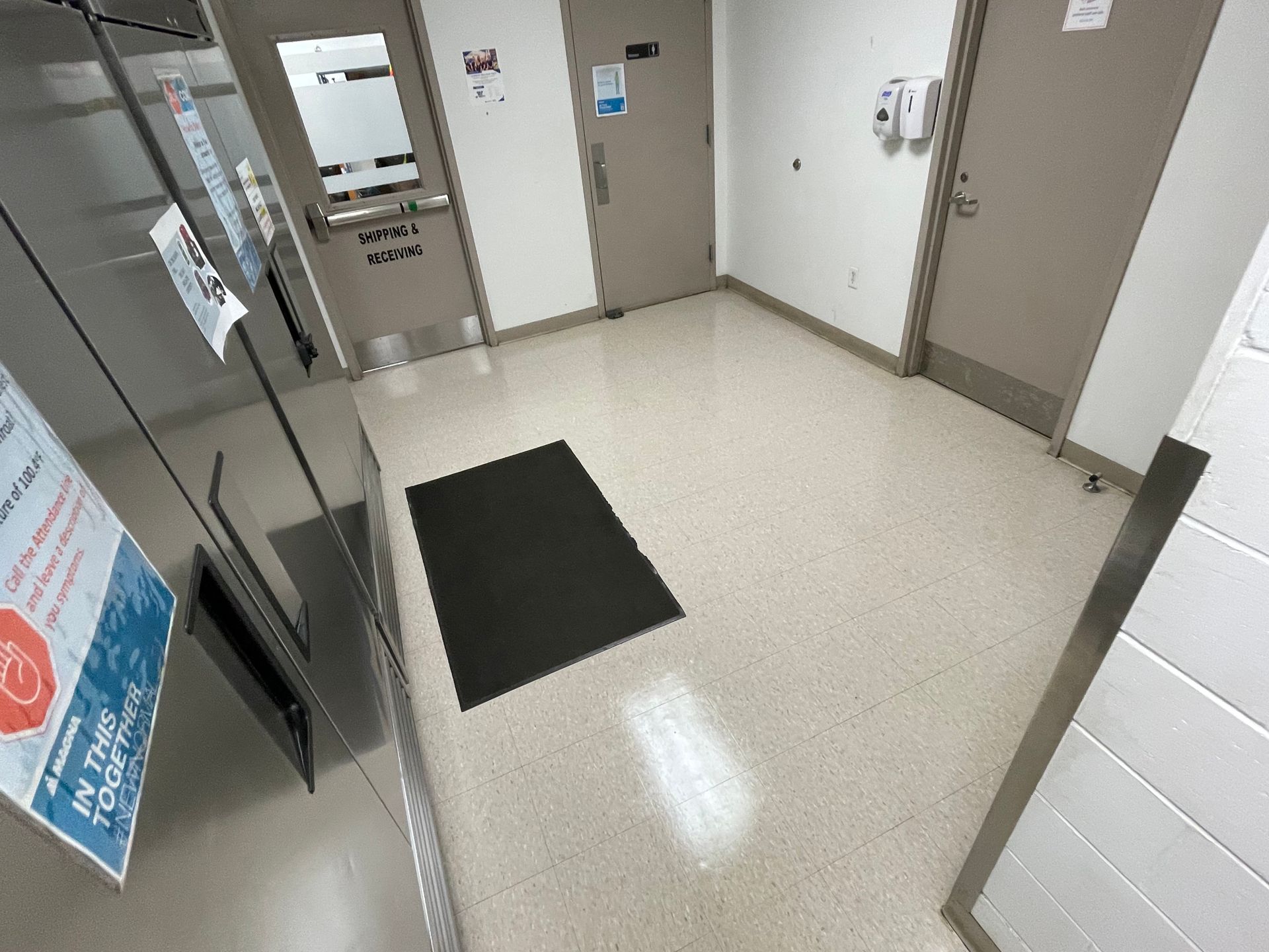 A hallway with a black mat on the floor.