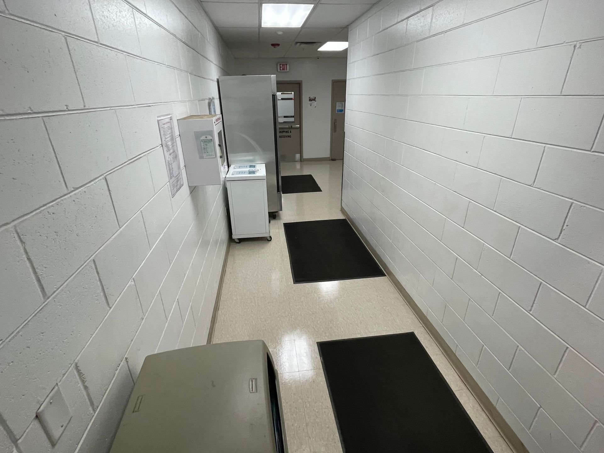 A long hallway with white brick walls and black mats
