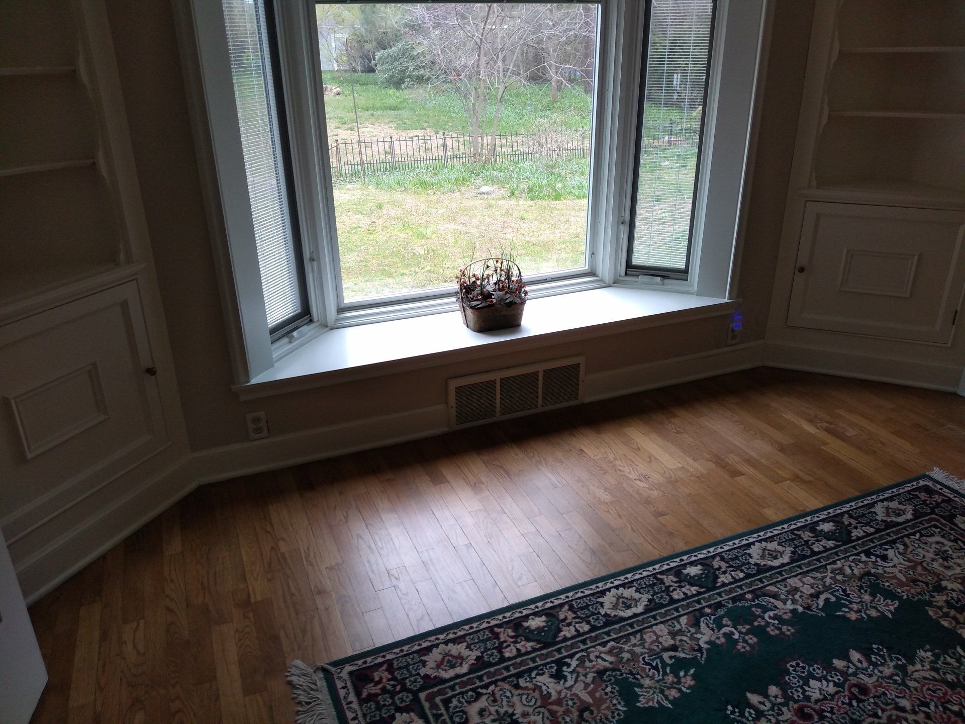 A living room with hardwood floors , a rug and a window.