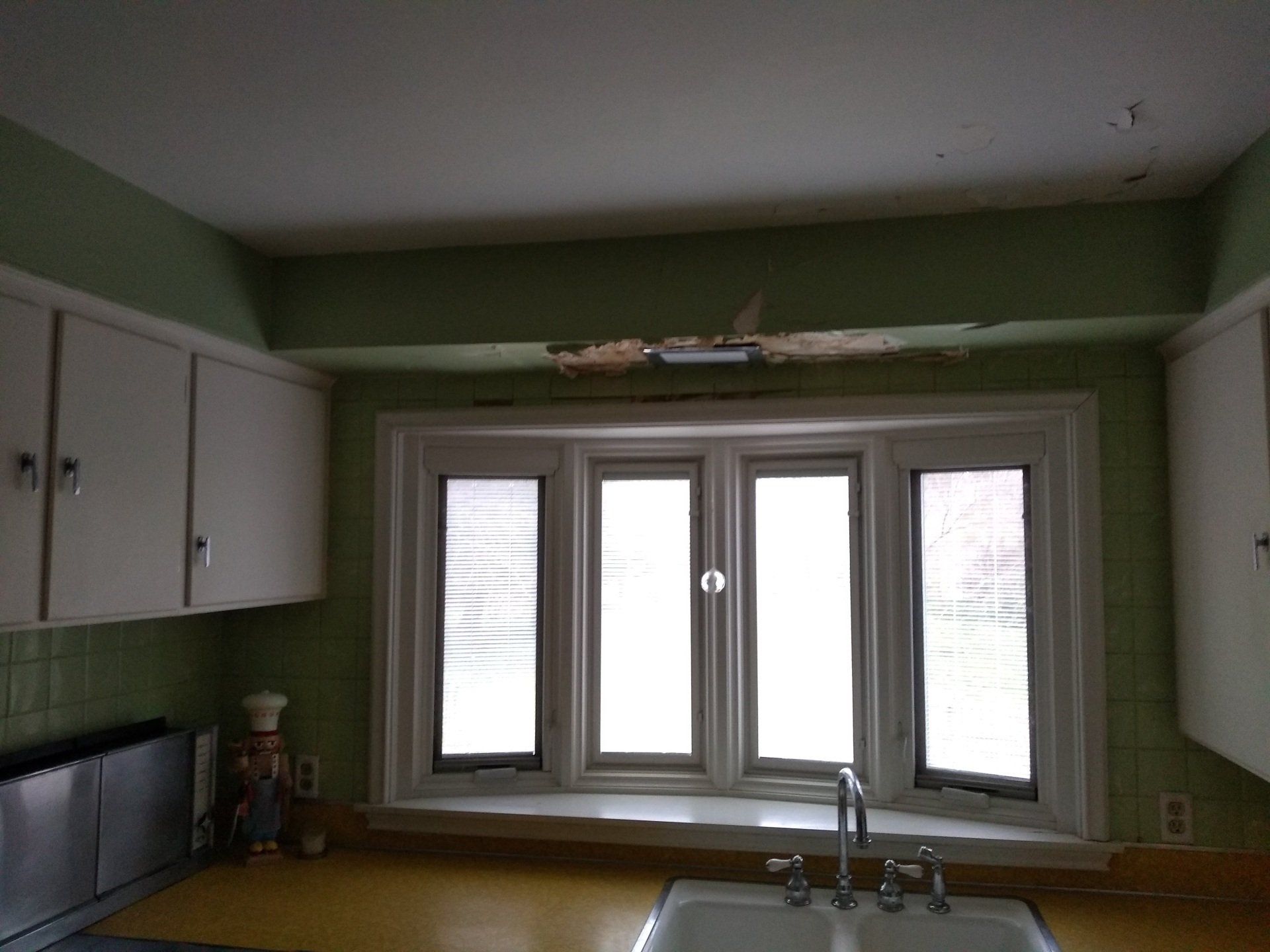 A kitchen with a sink , cabinets , and a window.