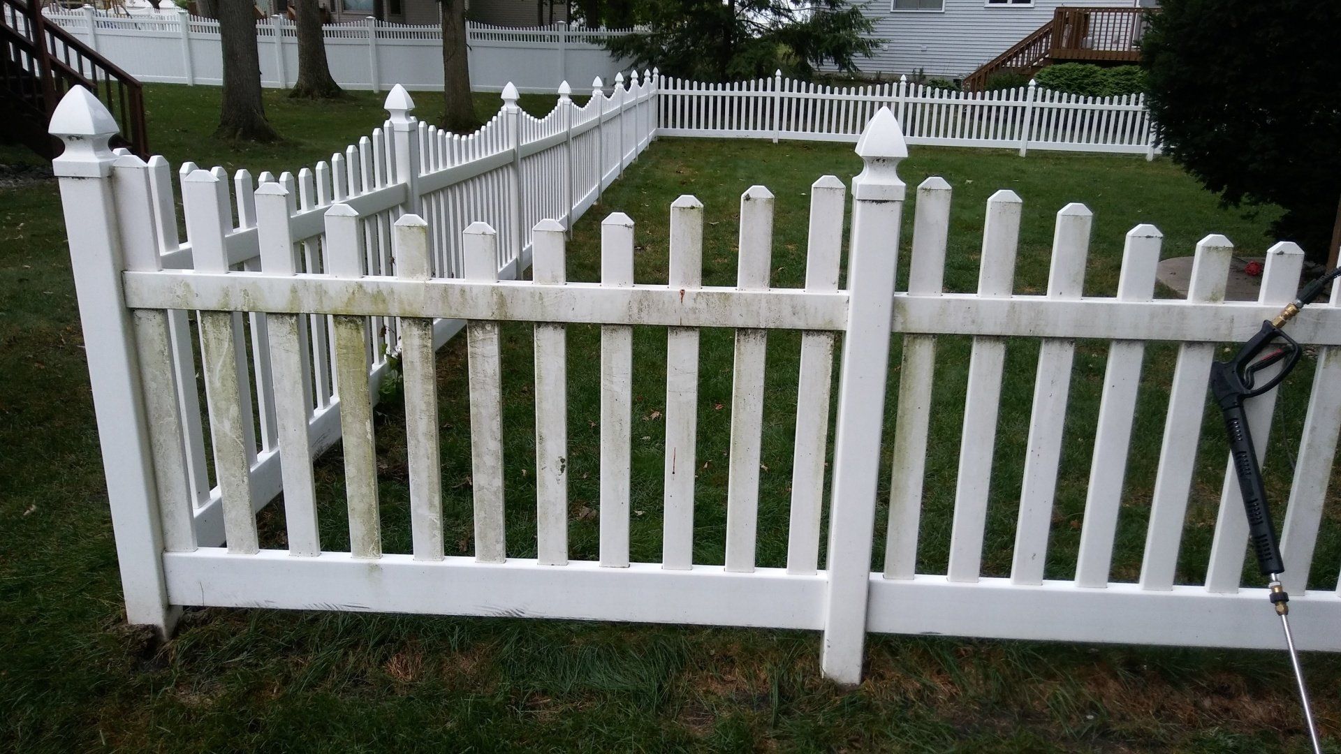 A white picket fence is sitting in the grass in front of a house.