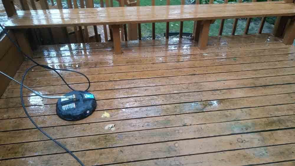 A wooden deck with a bench and a pressure washer on it.