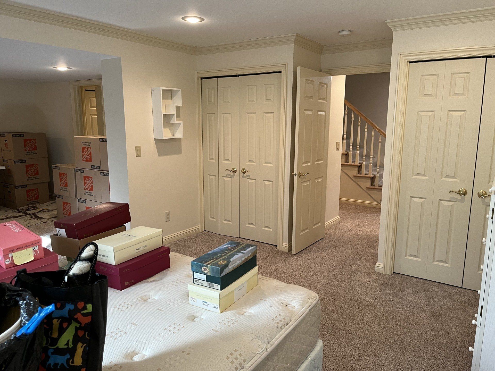 A basement with a mattress , boxes , and a staircase.