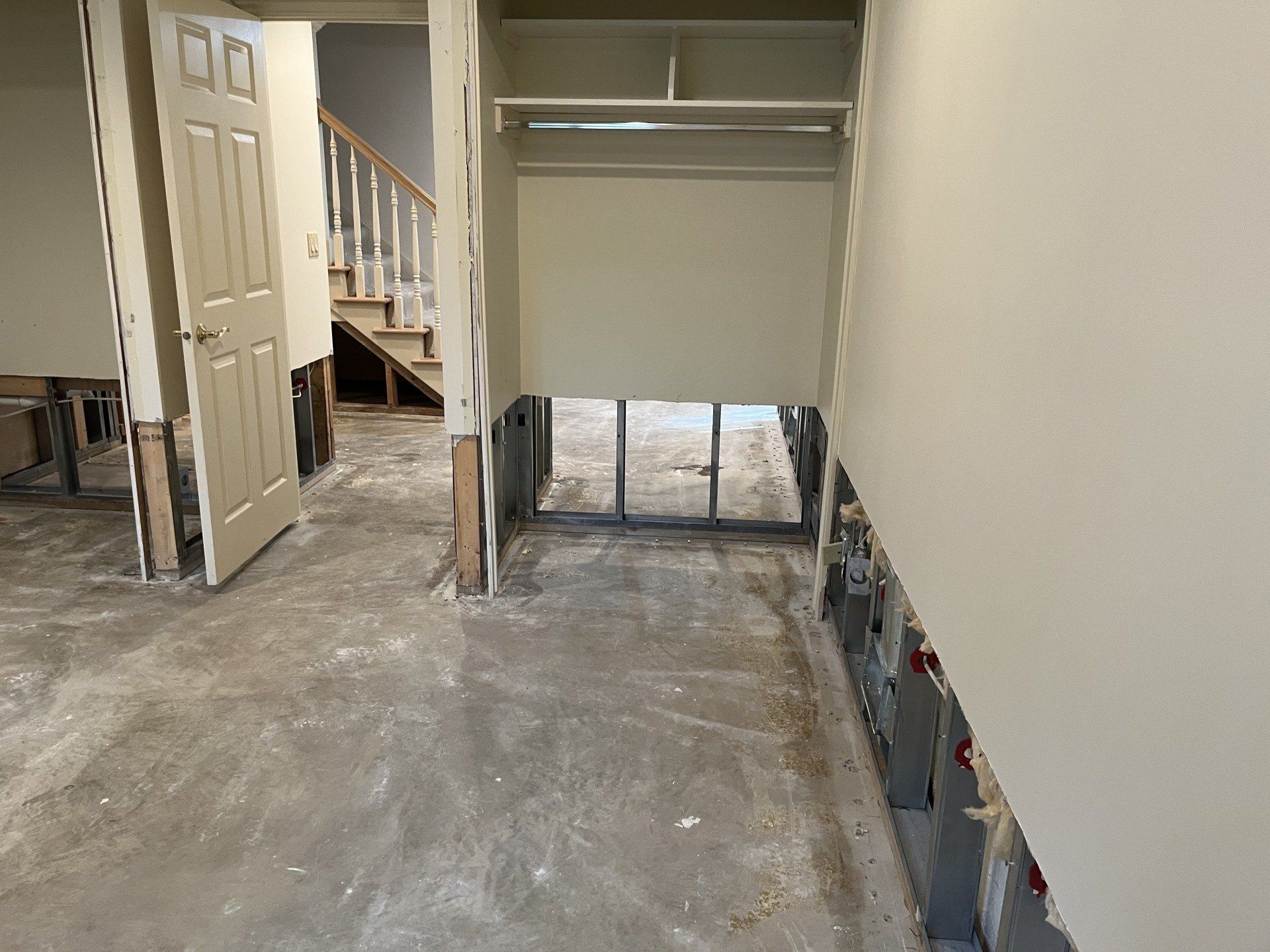 A hallway with a closet and stairs in a house under construction.