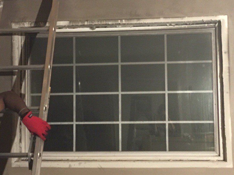 A person wearing red gloves is working on a window