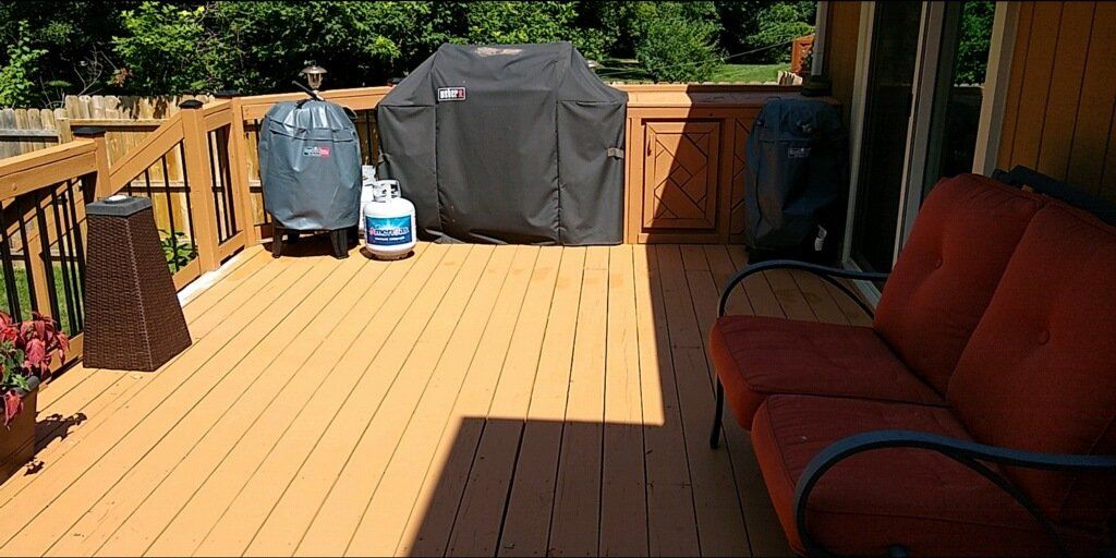 A wooden deck with a grill and a couch on it.