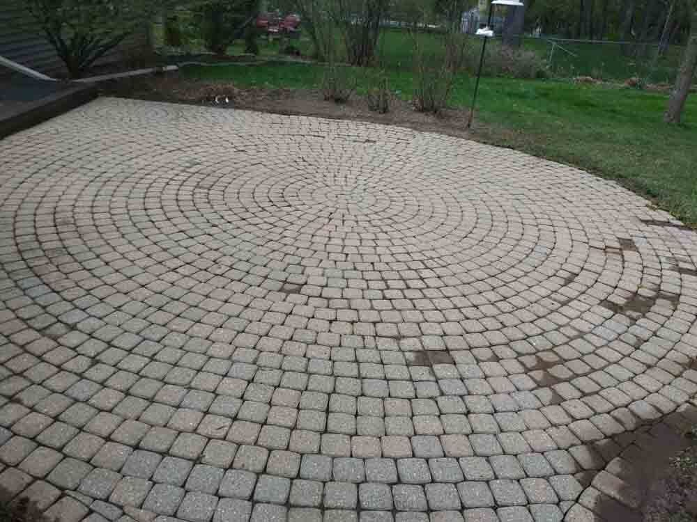 A brick patio with a circular pattern in the middle of it.