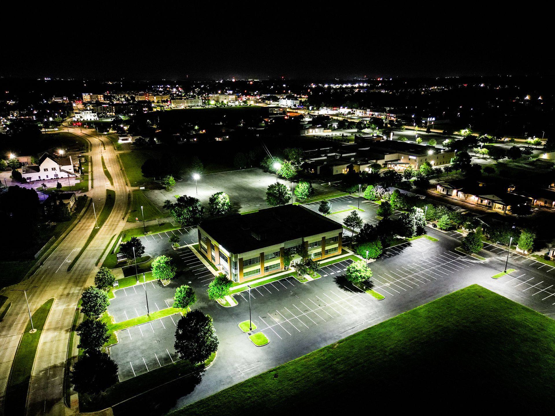 An aerial view of a building in a parking lot at night.