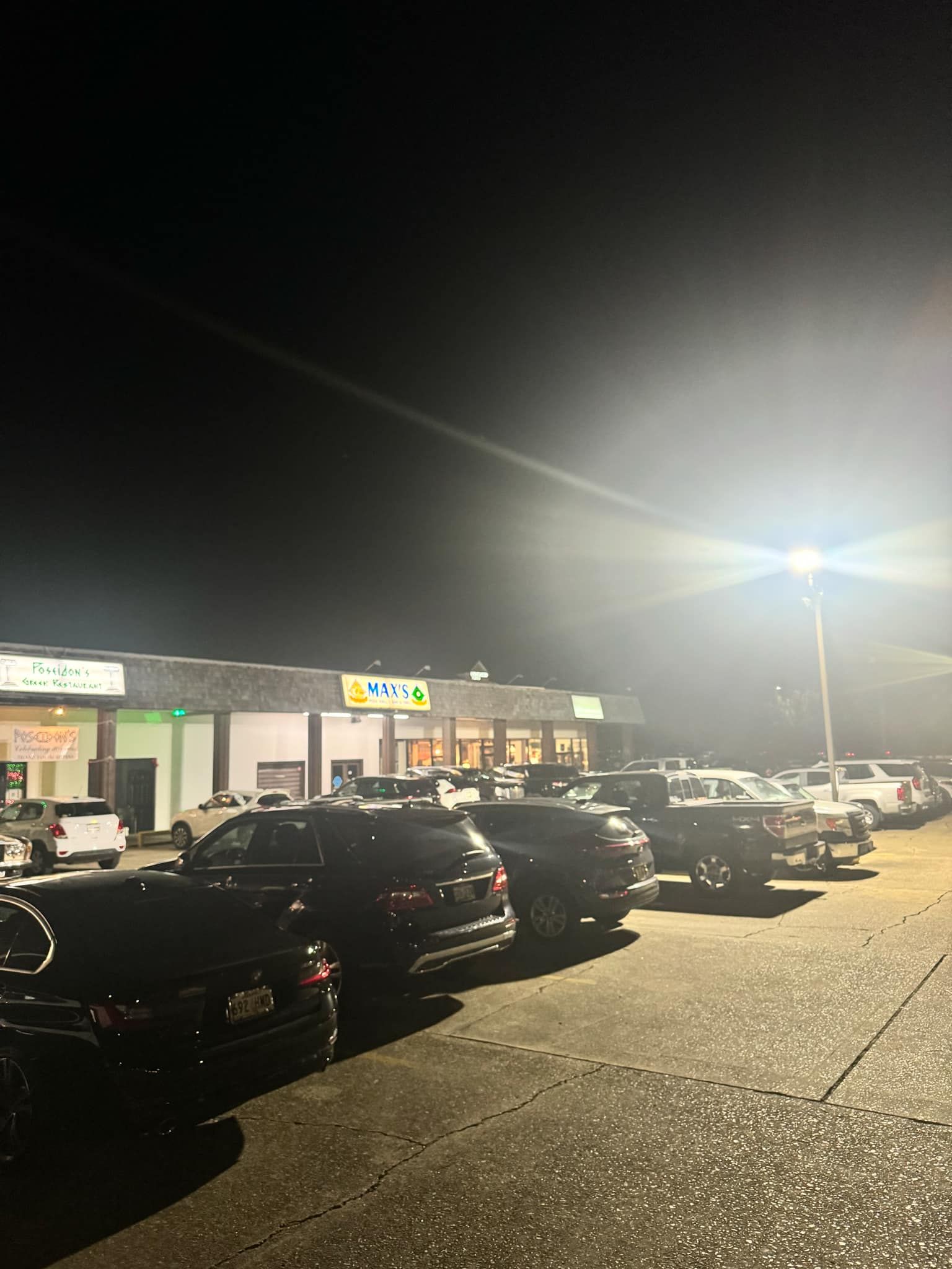 A lot of cars are parked in front of a building at night.
