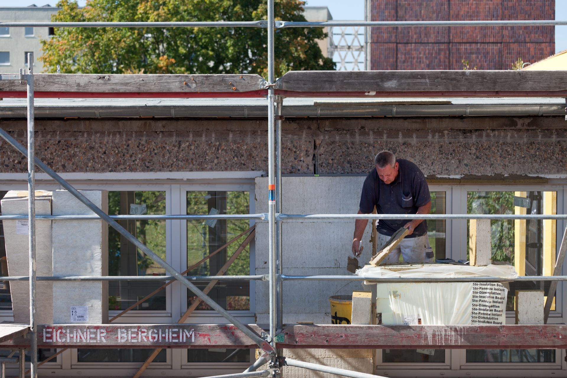 Ein Mann steht auf einem Gerüst vor einem Gebäude.