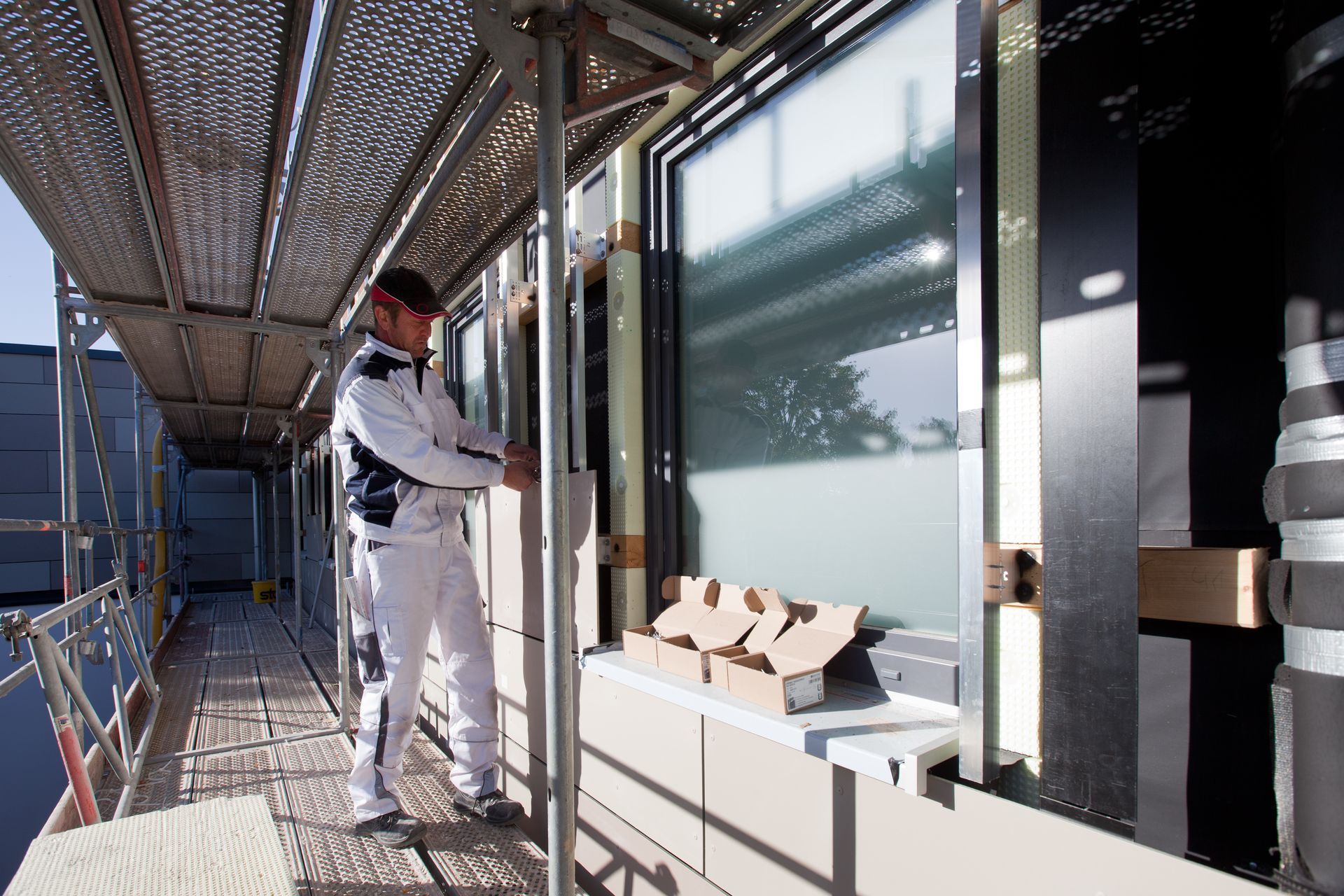 Ein Mann steht auf einem Gerüst neben einem Fenster.