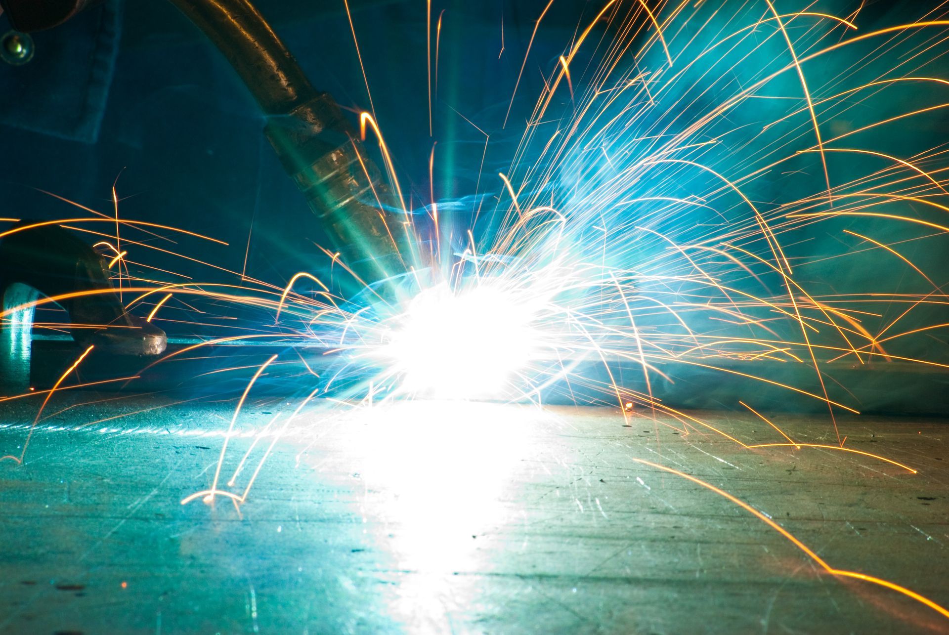 Eine Nahaufnahme einer Person, die ein Stück Metall schweißt, aus dem Funken aufsteigen.