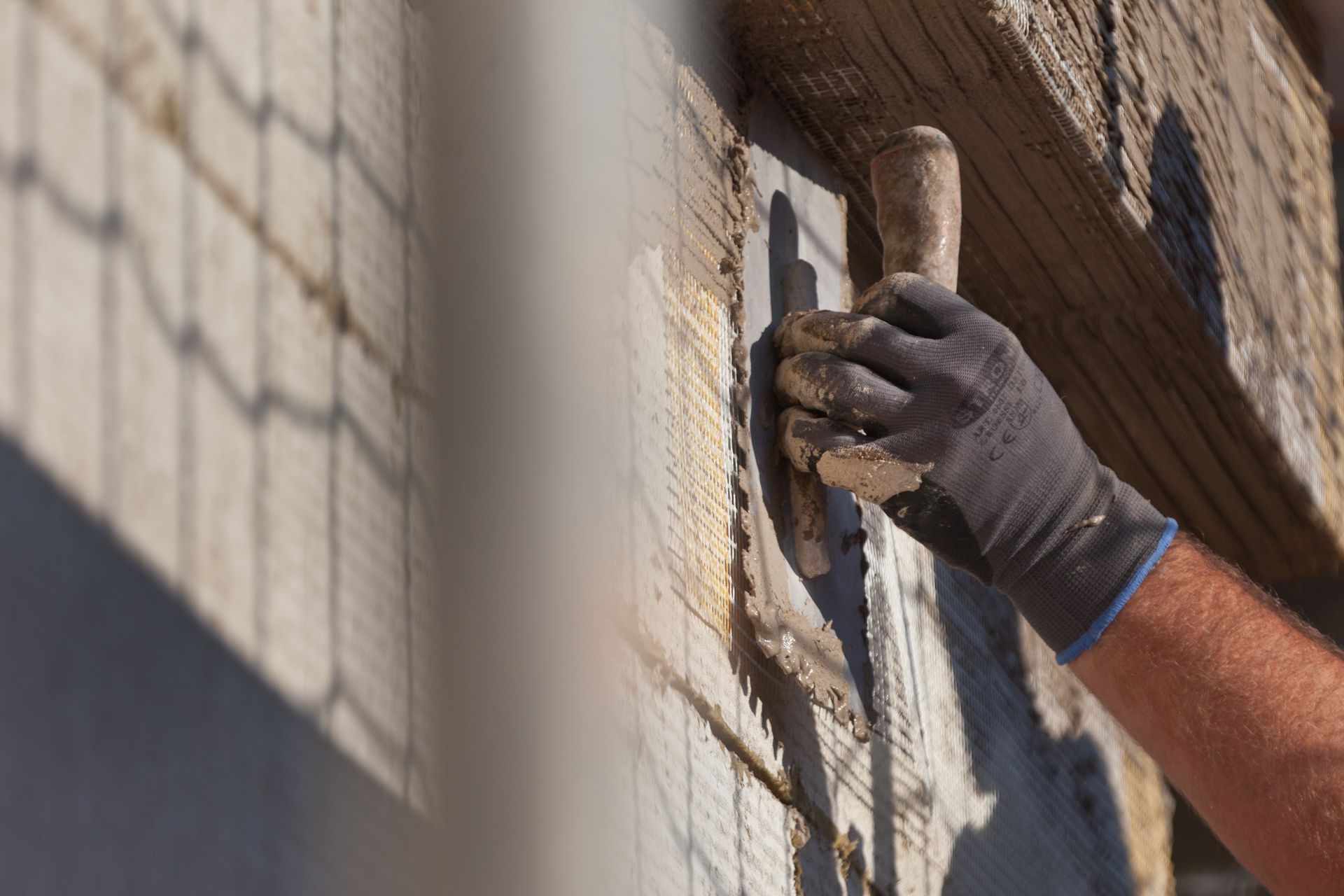 Ein Mann verputzt eine Wand mit einer Kelle.