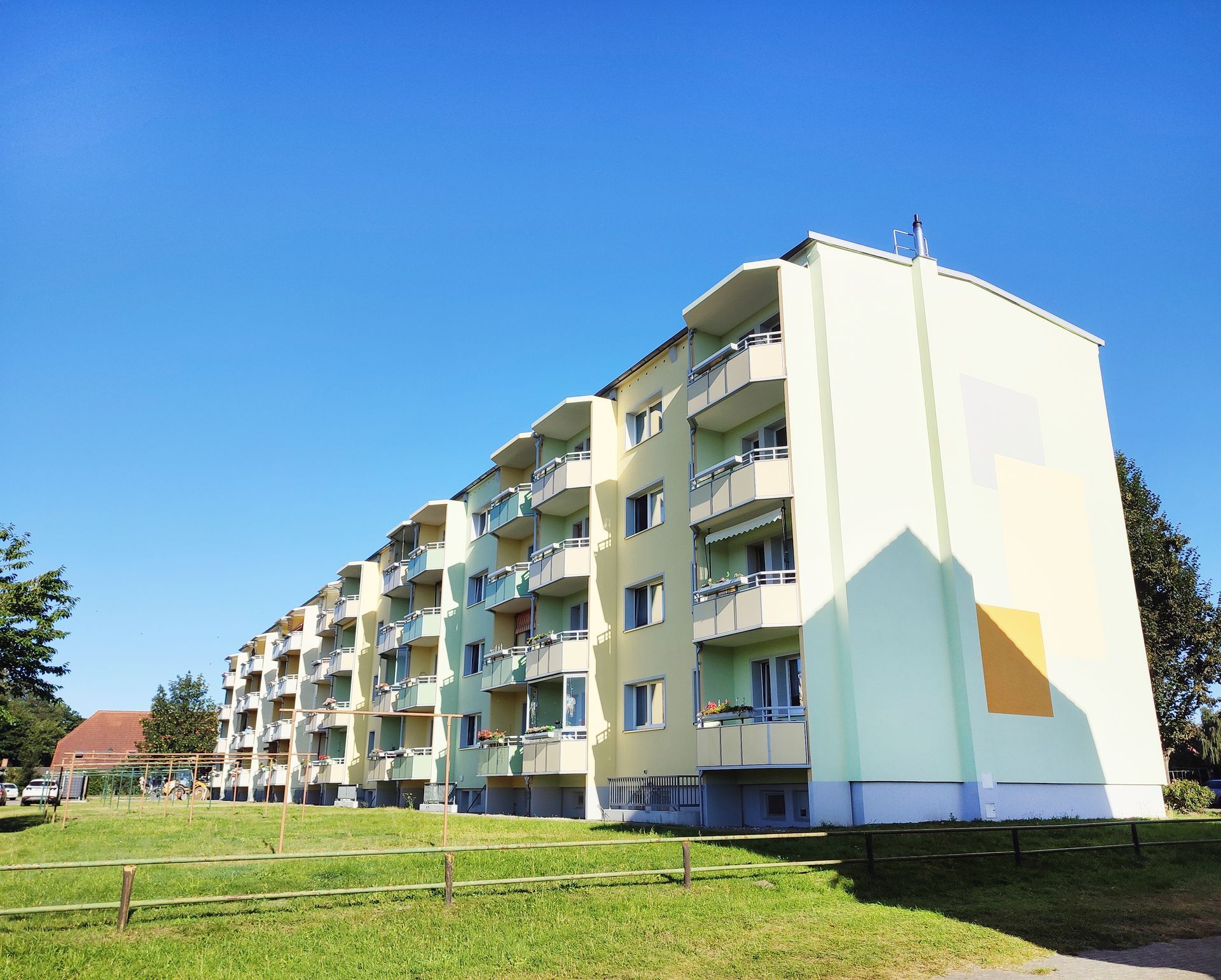 Ein Mehrfamilienhaus mit Balkonen und einer Wiese davor