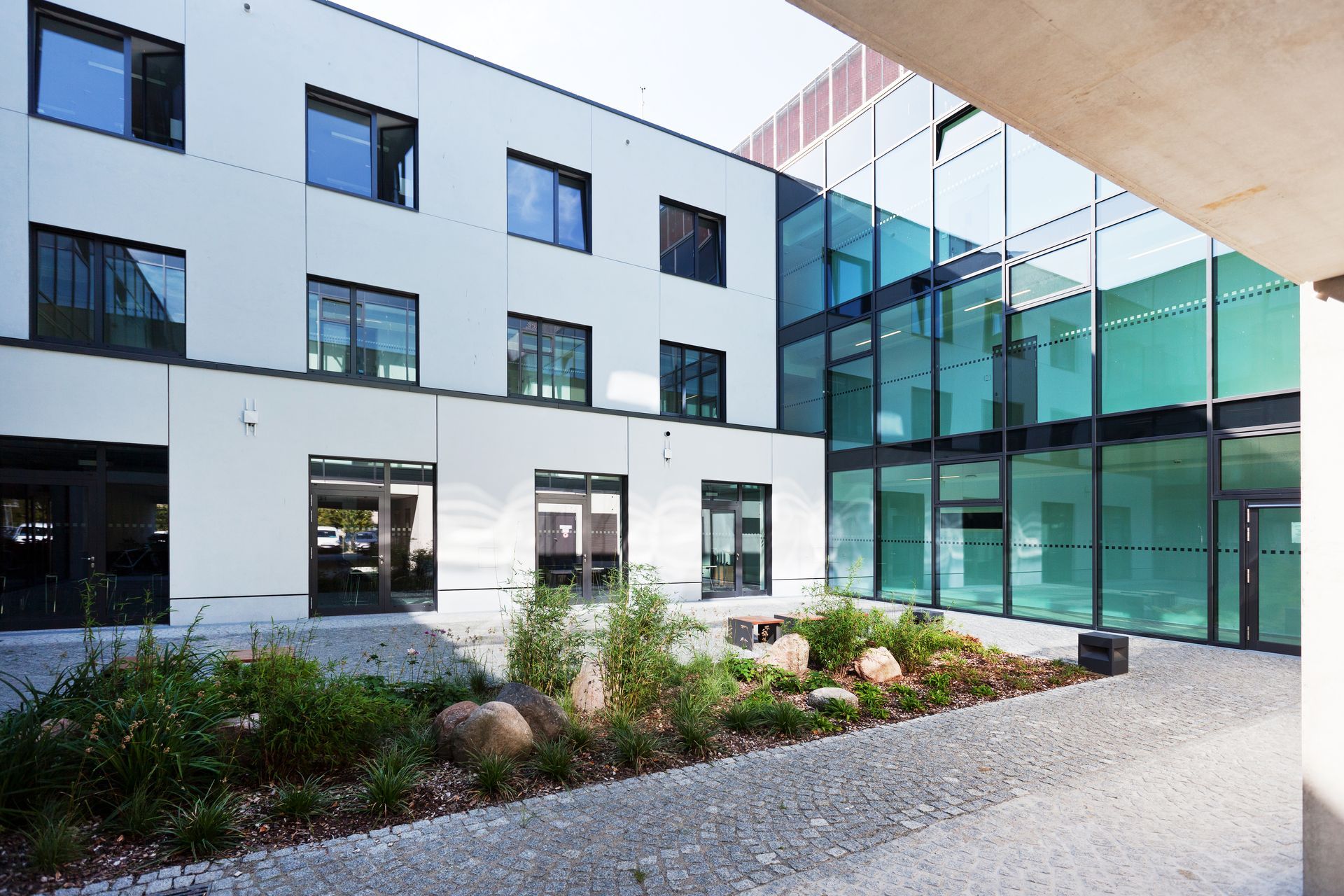 Ein Innenhof des Uniklinikums Greifswald mit Blick auf eine Gebäudeecke und Beet in der Mitte.