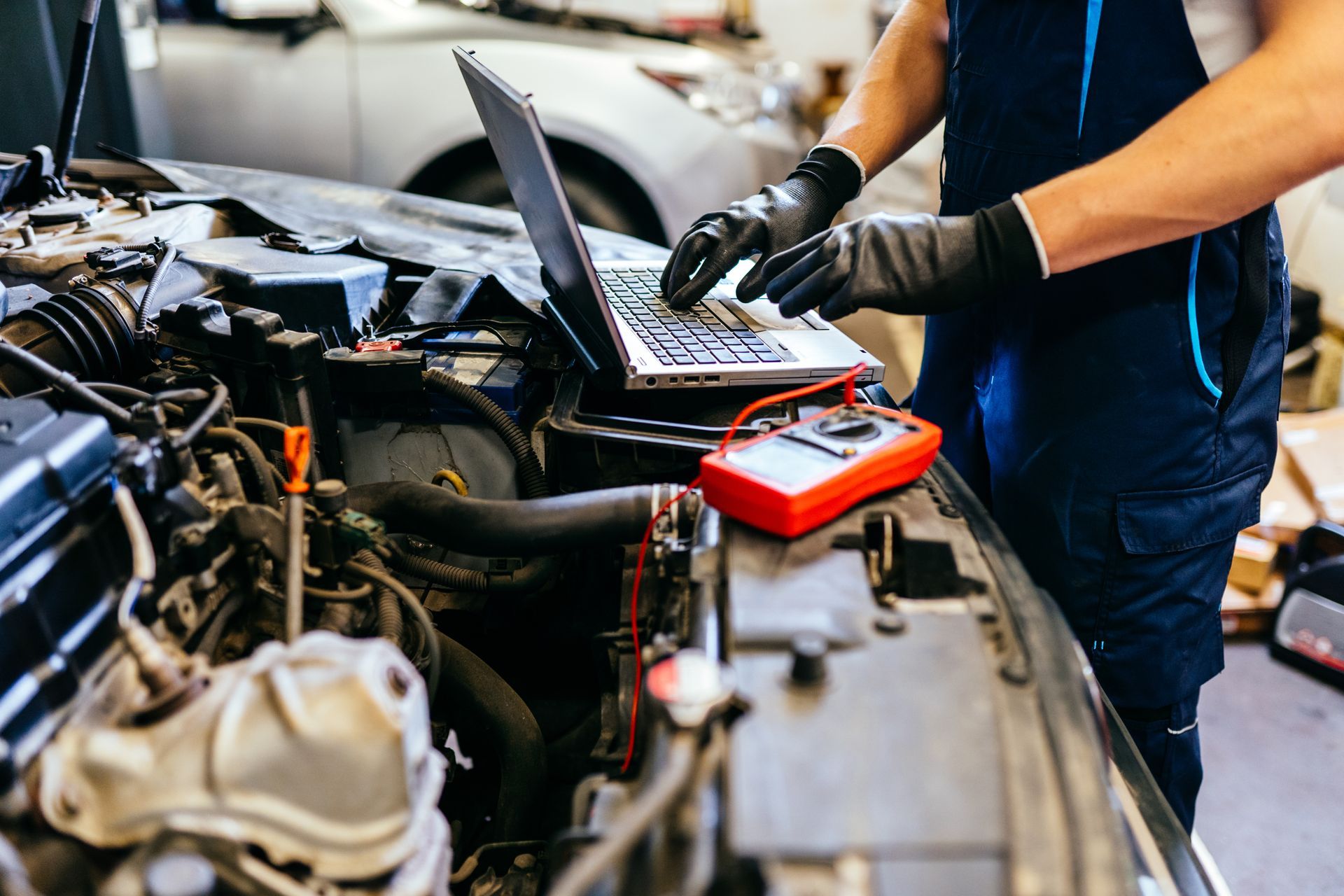 An auto electrician is using a computer in an auto repair shop to perform auto electrician services.