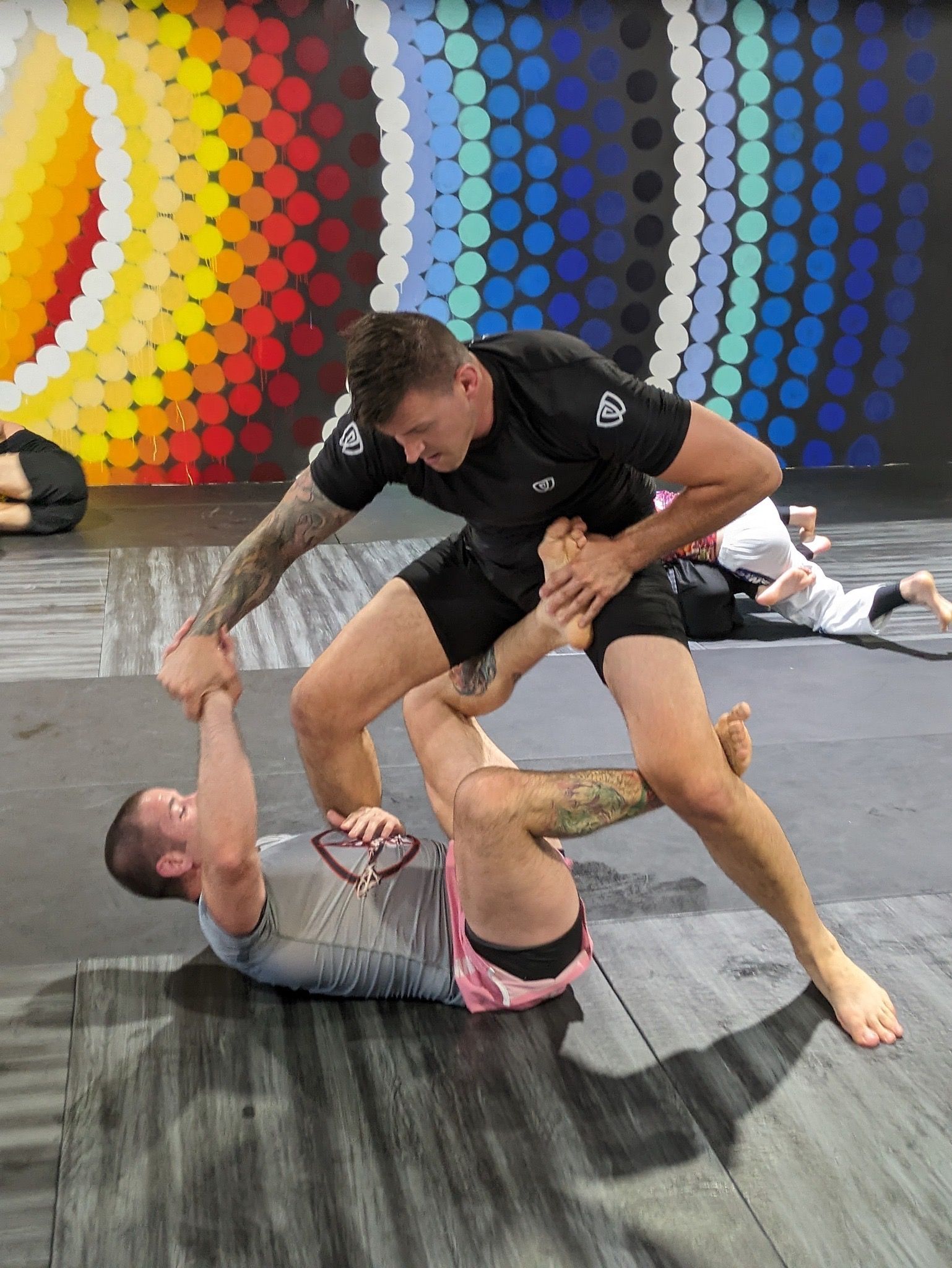 Two men are wrestling on a mat in a gym