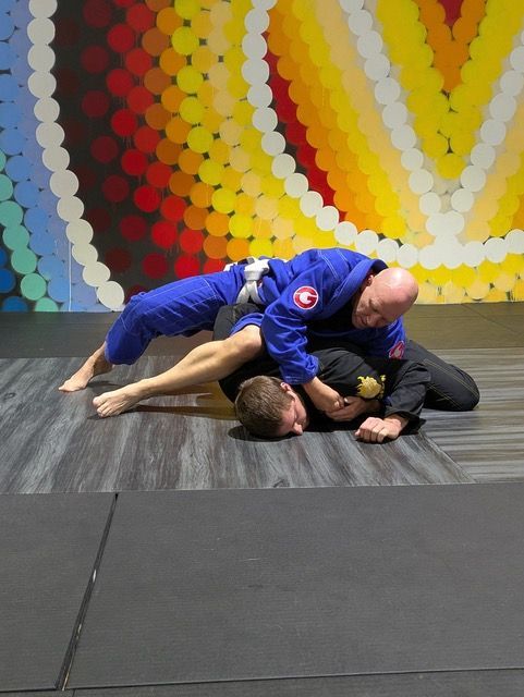 Two men are wrestling on a mat in front of a colorful wall