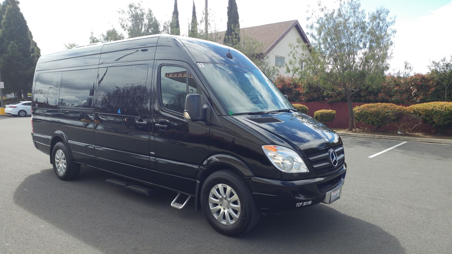 A black van is parked in a parking lot in front of a house.