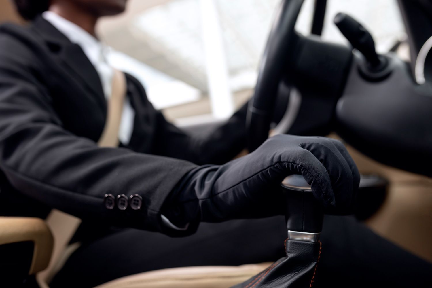 A man in a suit and tie is driving a car.