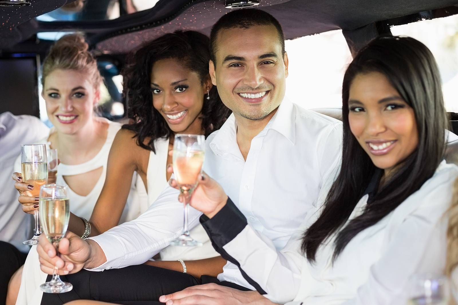 A group of people are sitting in a limousine toasting with champagne glasses.