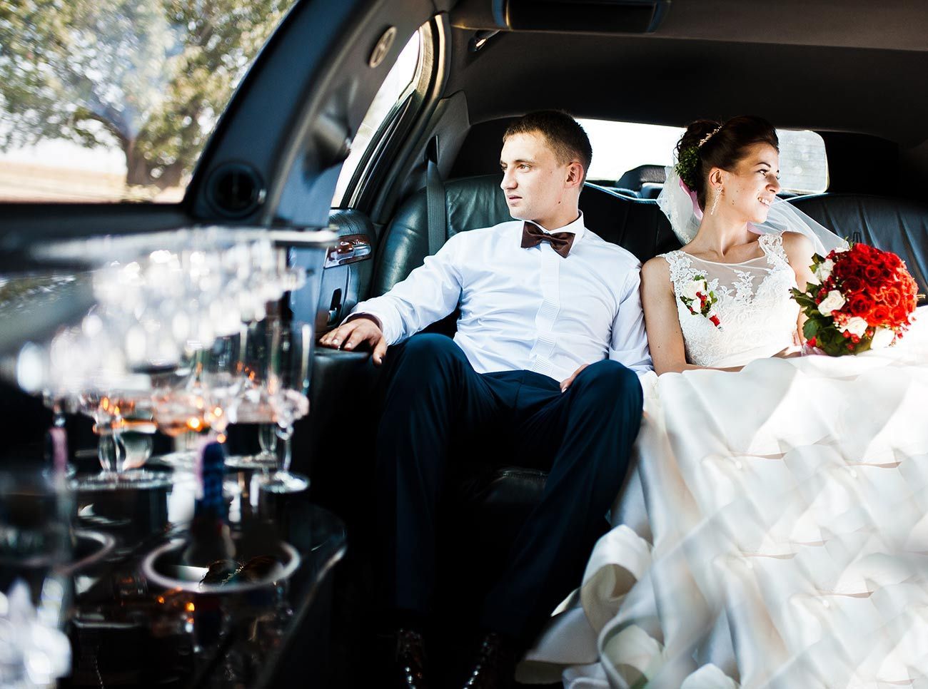 A bride and groom are sitting in the back of a limousine.