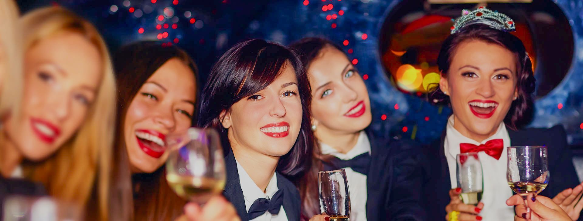 A group of women are standing next to each other holding wine glasses at a party.
