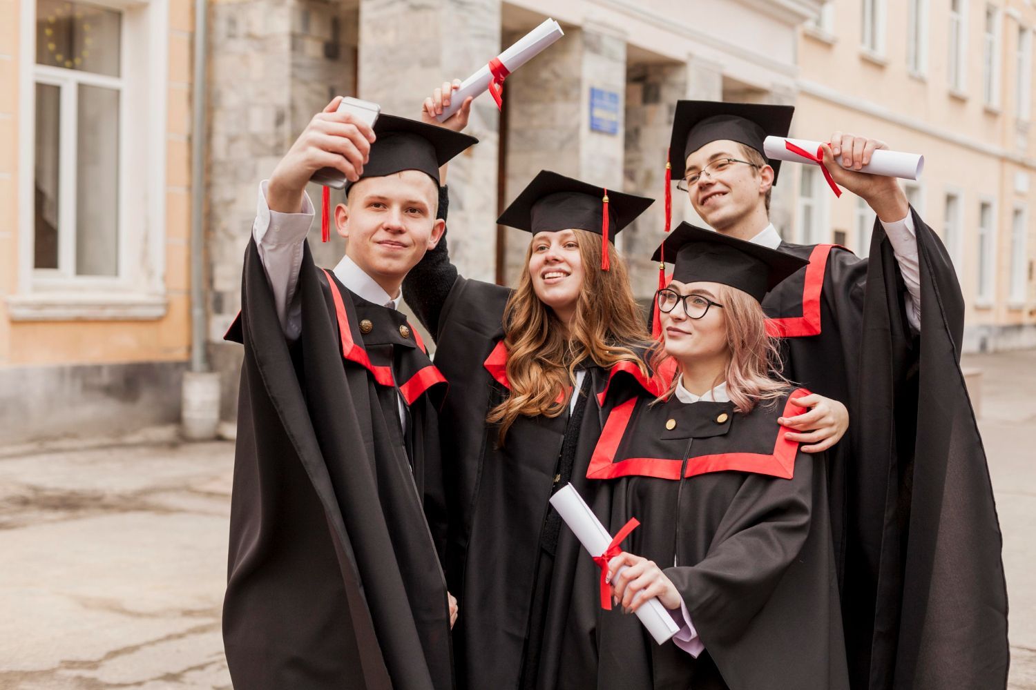 A group of graduates are standing in front of a building holding their diplomas.