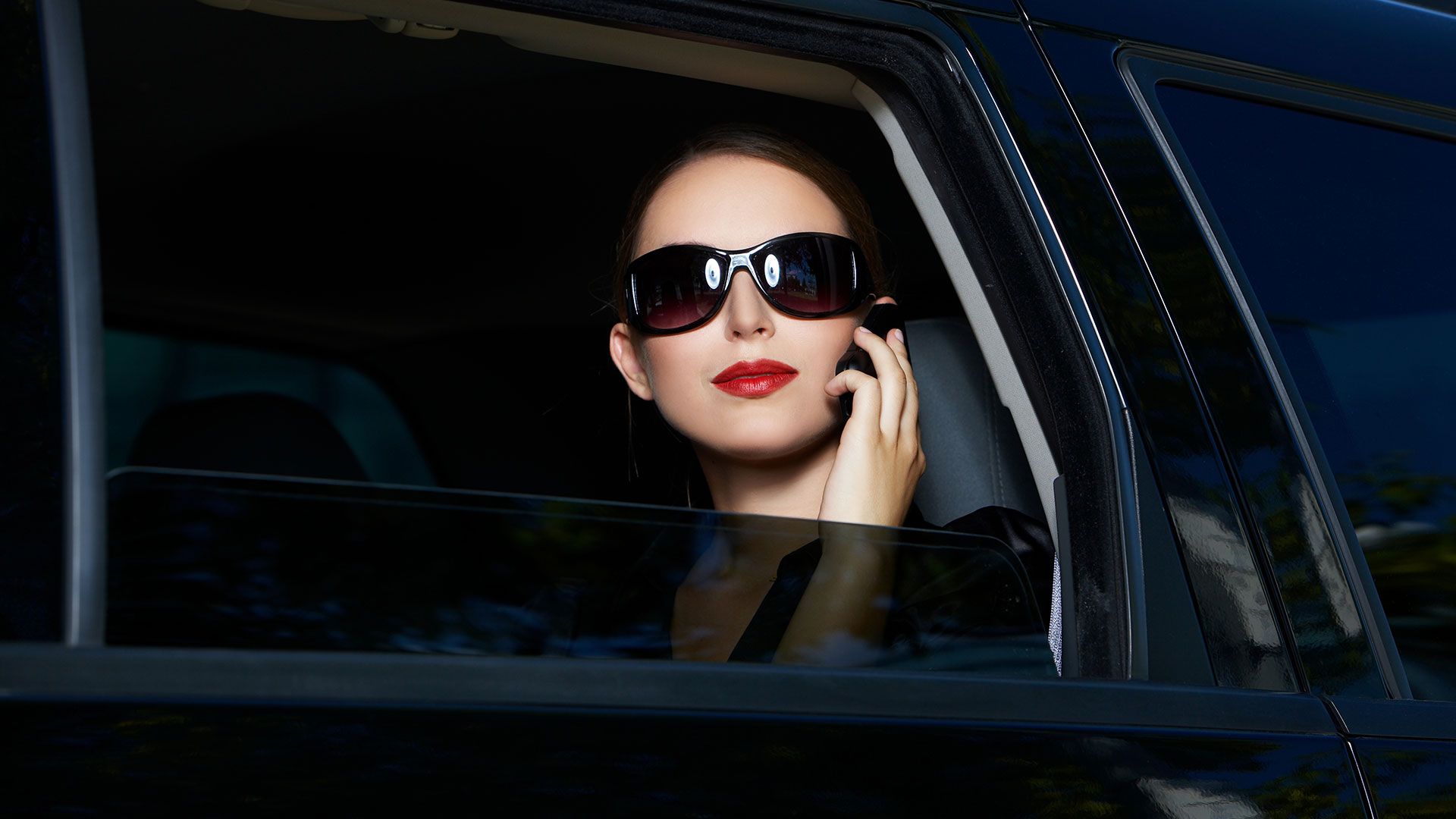 A woman is sitting in the back seat of a car.
