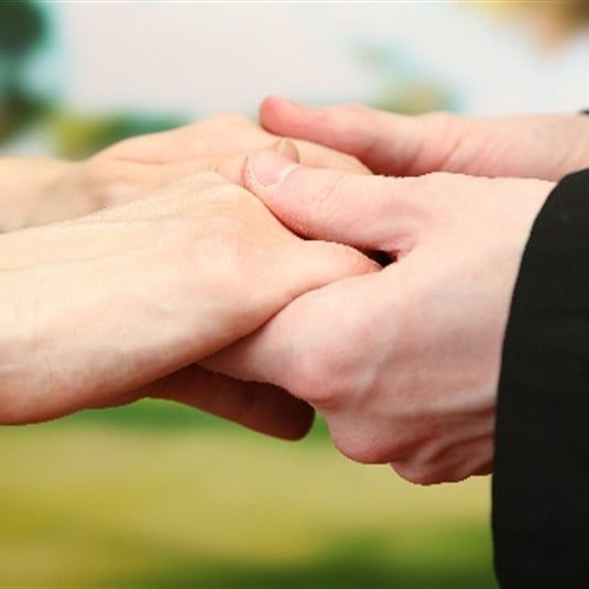 A man in a suit is holding a woman's hand.