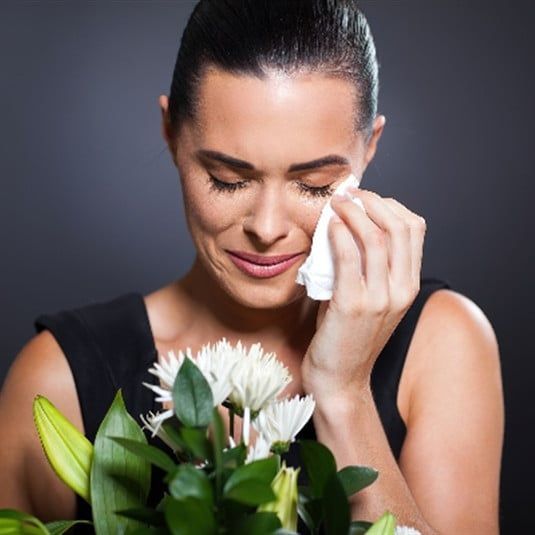 A woman is crying while holding a bouquet of flowers.