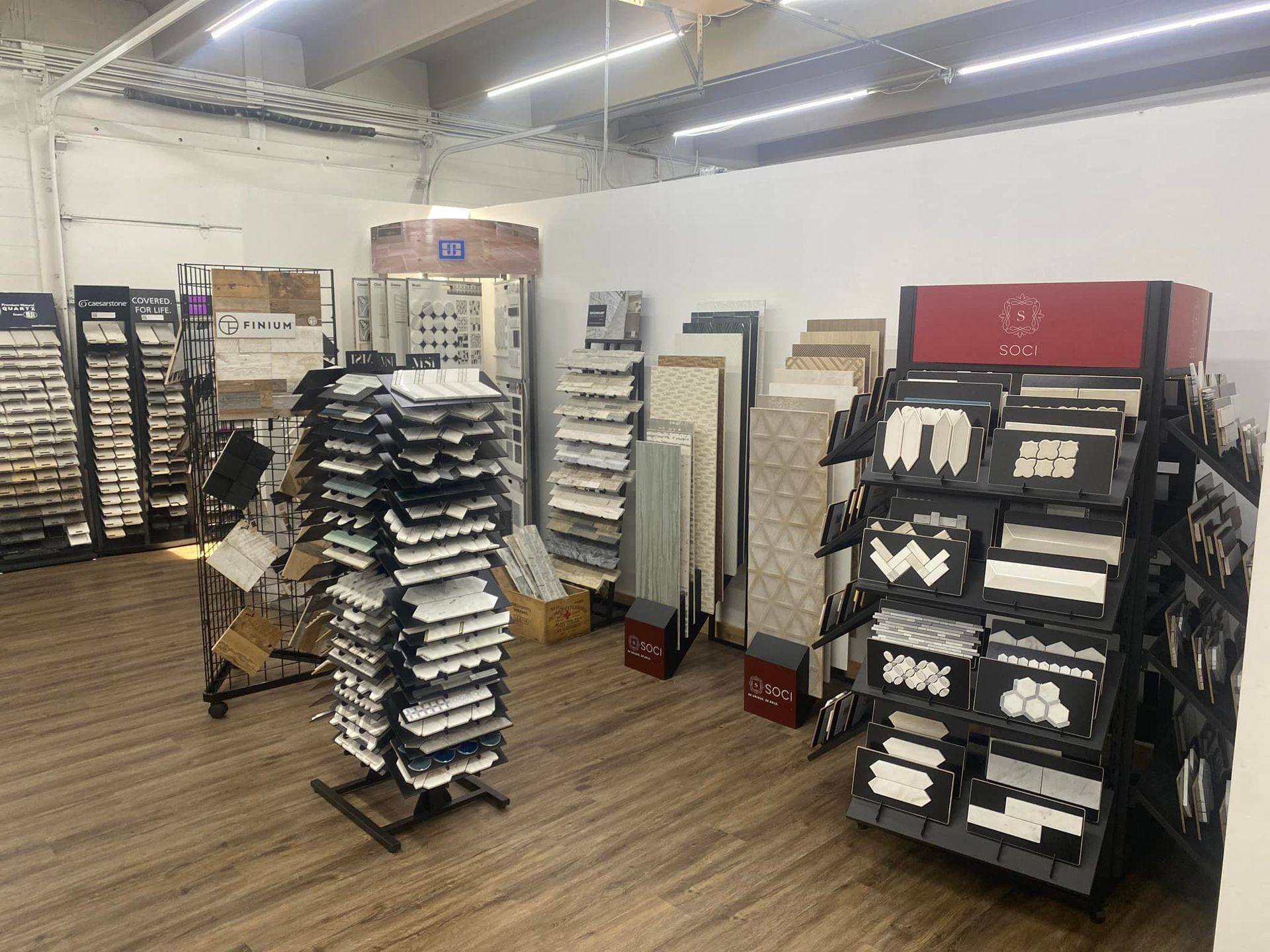 Displays of tile samples in a brightly lit showroom with wood-look flooring.