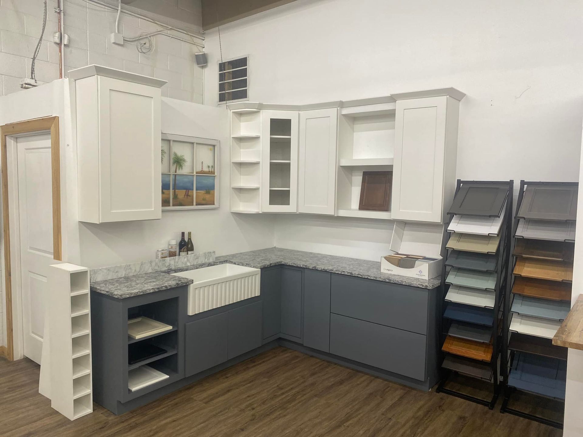 Kitchen cabinets in a showroom with gray and white cabinetry, granite countertop, and color samples.