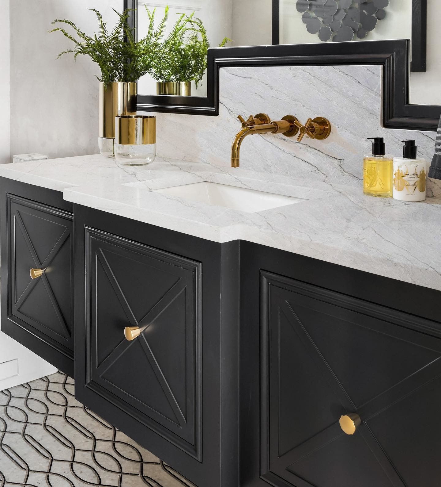 Bathroom vanity with black cabinets, marble countertop, and gold fixtures.