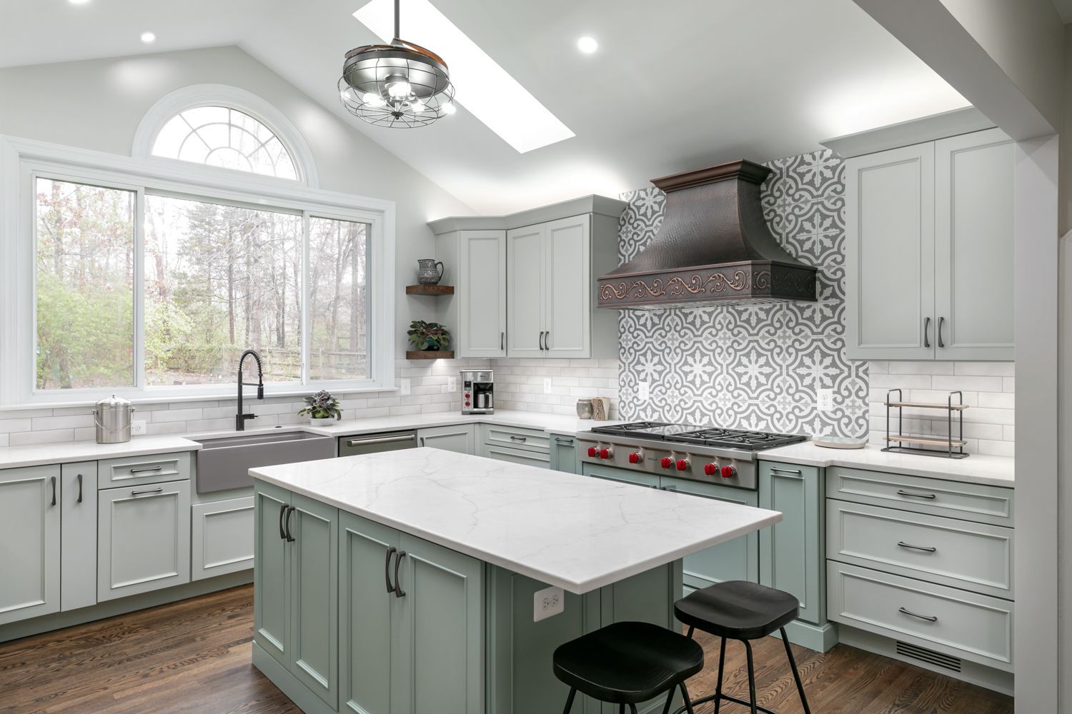 Modern kitchen with sage green cabinets, white countertops, and a large island.