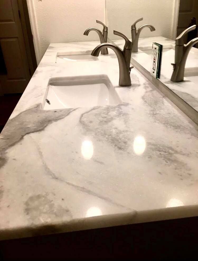 Marble bathroom countertop with two sinks and silver faucets.