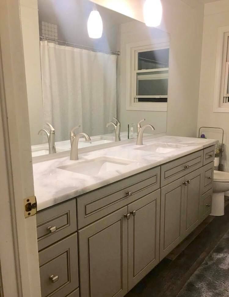 Bathroom with a gray vanity, marble countertop, double sinks, and a large mirror.