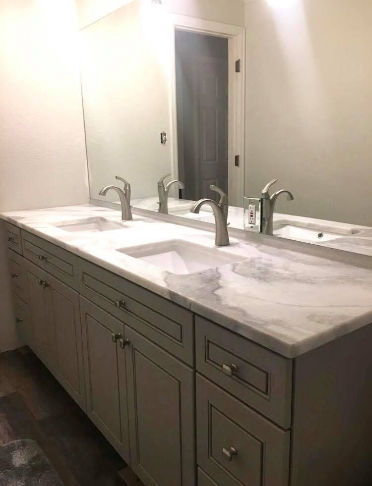 Gray double sink vanity with marble countertop and silver faucets in a bathroom.