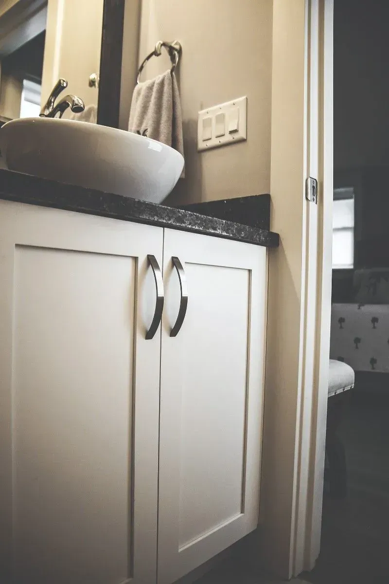 White bathroom vanity with dark countertop and vessel sink.