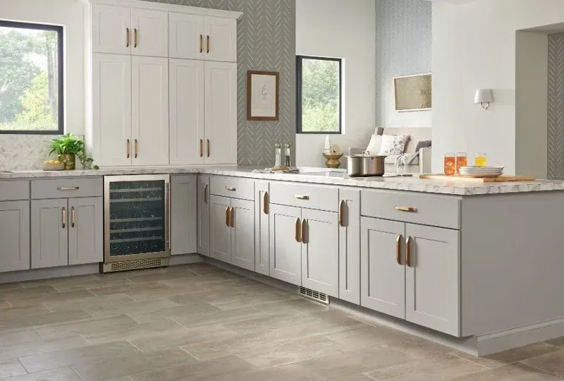 Gray and white kitchen with cabinets, countertops, and a wine fridge. Copper hardware, tile floor.